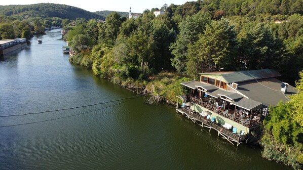 A riverside wooden dock with a restaurant and outdoor seating overlooking the water.