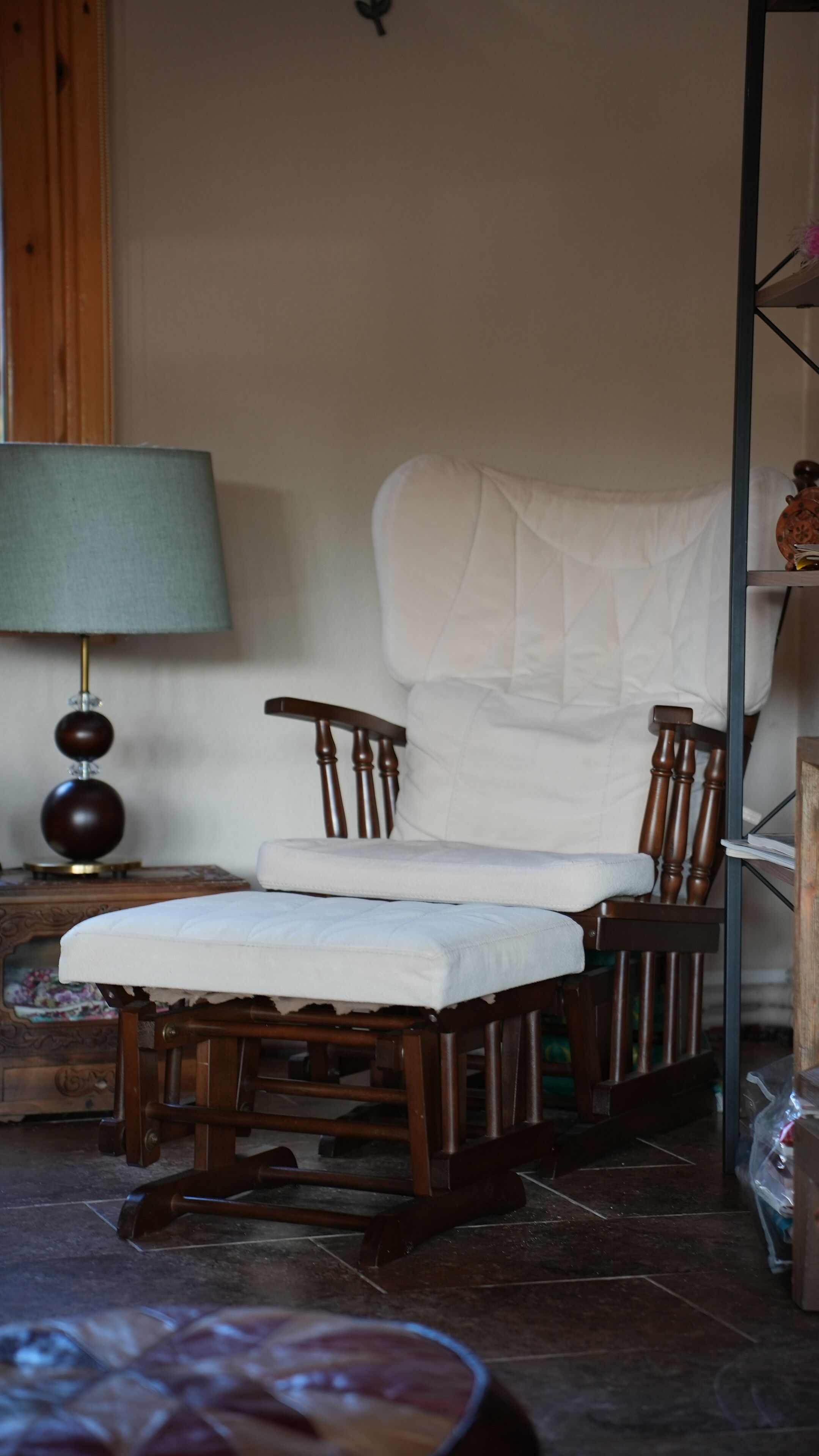 A room with a wooden chair and a small table with a lamp.