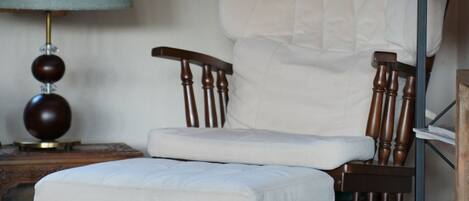 A room with a wooden chair and a small table with a lamp.