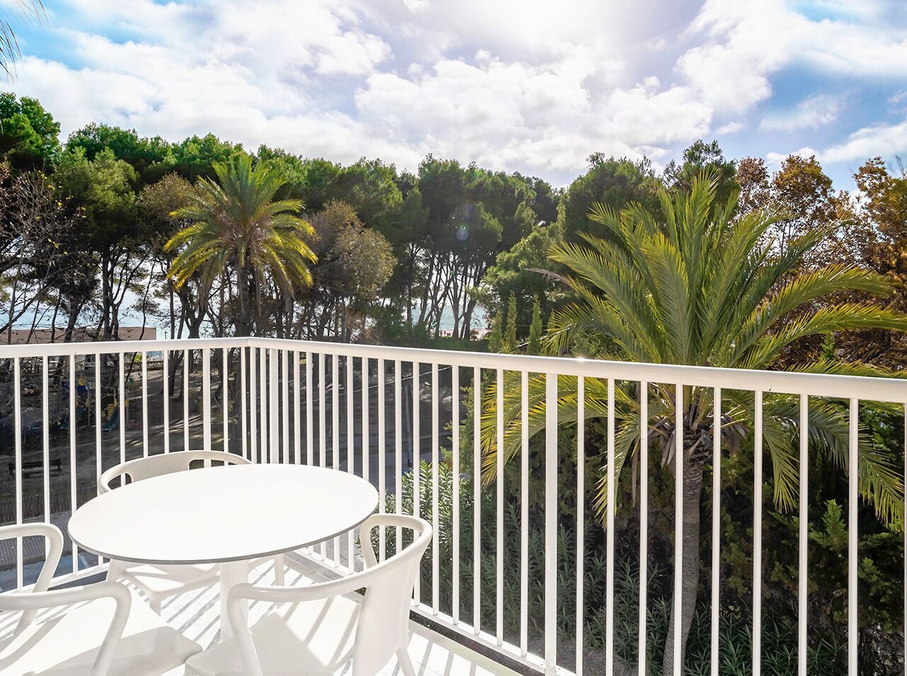 A balcony with a white railing, a round table, and chairs.