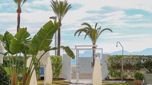 A stone pathway leading to a gated entrance with palm trees and a view of distant mountains.