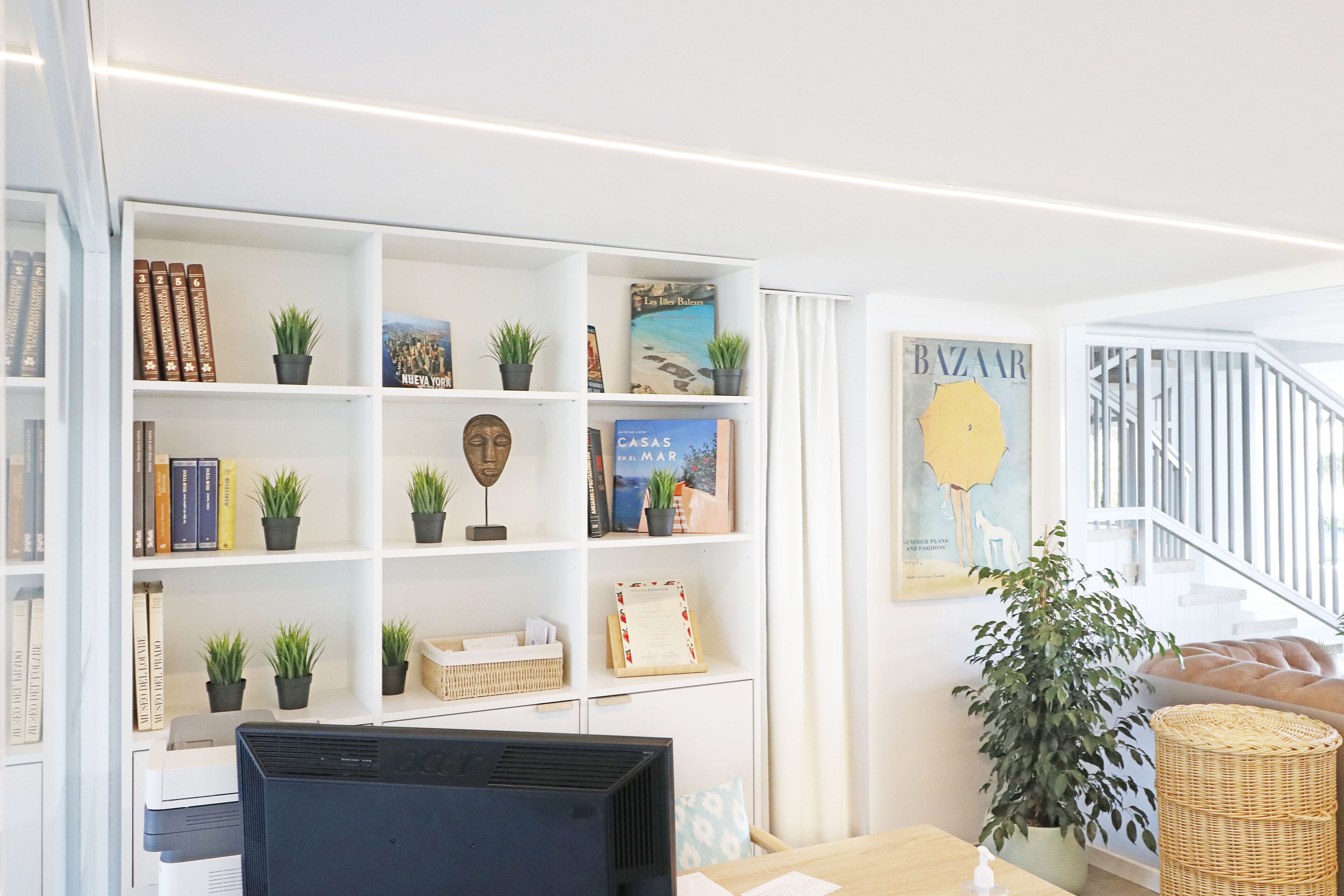 A modern interior with a bookshelf, a computer, and a large window.