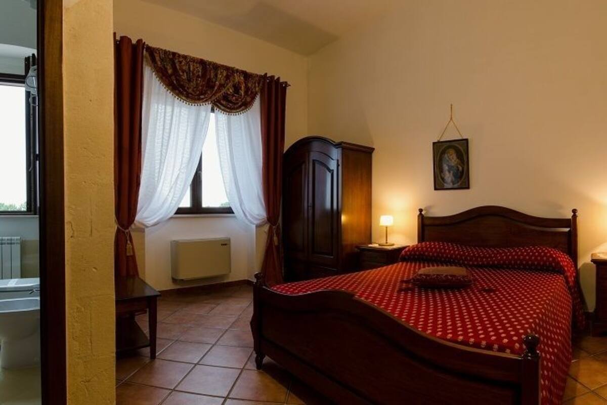 Une chambre à coucher avec un grand lit, deux tables de chevet, une armoire et une fenêtre avec des rideaux.