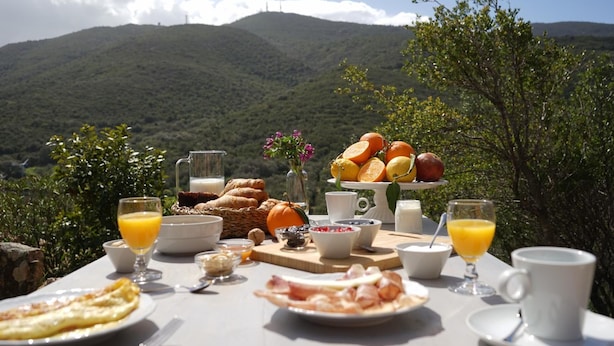 A breakfast table set outdoors with a scenic mountain view in the background.