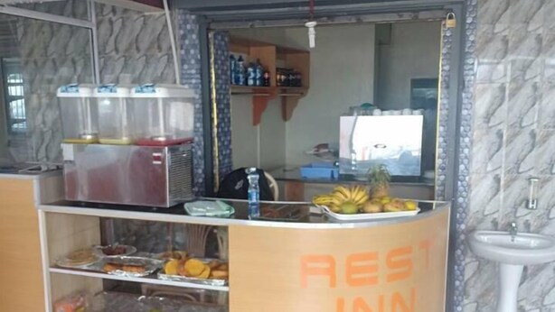 A small food kiosk labeled "REST INN" with a variety of snacks and beverages on display.