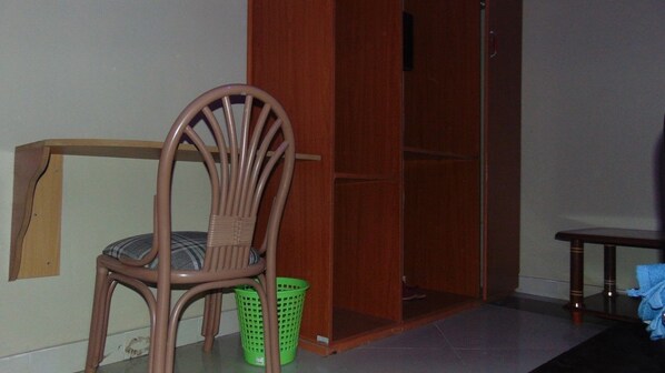 A room with a wooden chair, a green basket, and a wooden wardrobe.