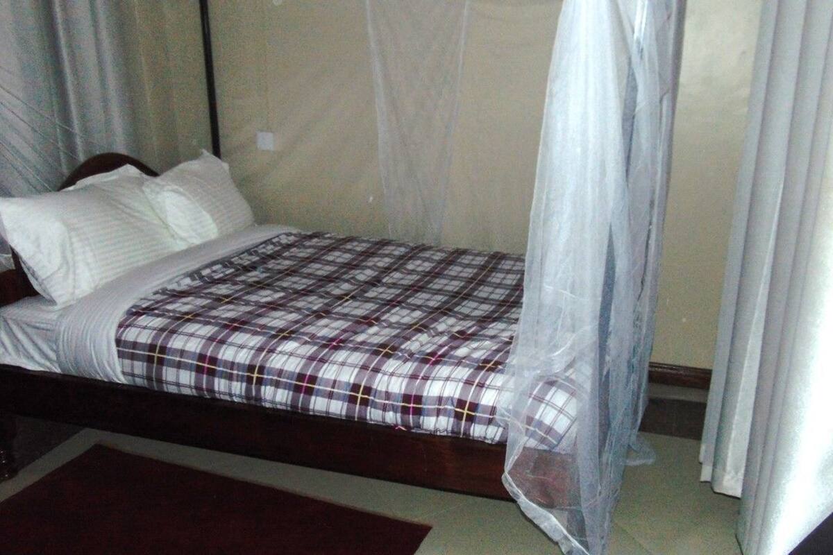 A single bed with a checkered bedspread, a white pillow, and a mosquito net.