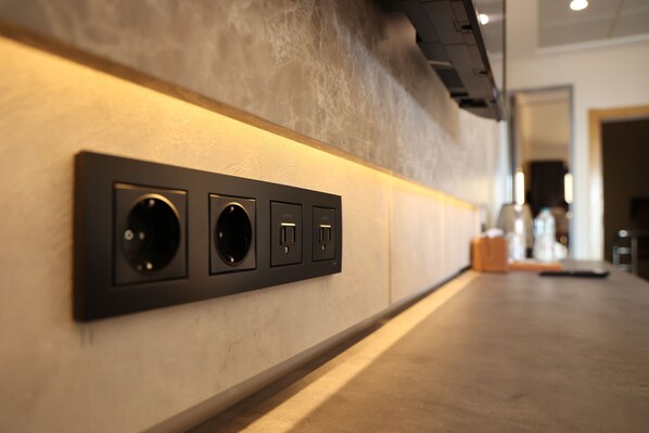 Un interior moderno con un largo pasillo estrecho, que presenta un tablero eléctrico de pared con tres enchufes y dos puertos USB.