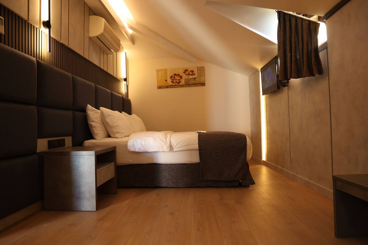 A modern bedroom with a bed, bedside tables, and a painting on the wall.