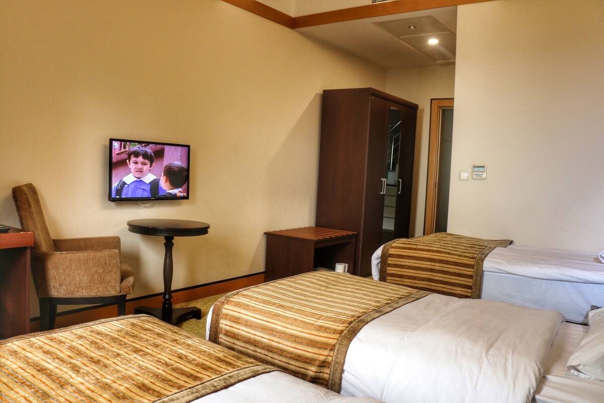 A hotel room with two beds, a television, a chair, and a small table.