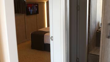 Habitació d'hotel amb un llit, una televisió penjada a la paret i un terra de fusta.