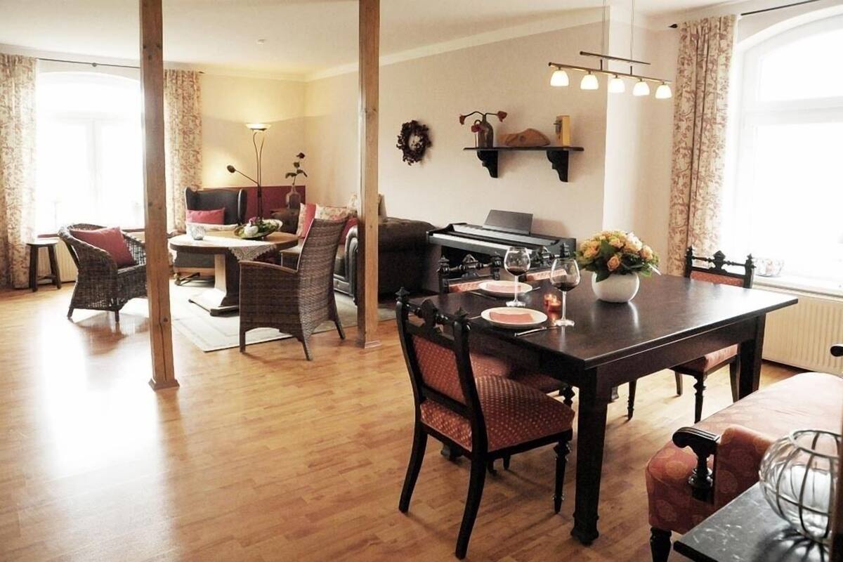 Un comedor con mesa de madera, sillas y un piano.