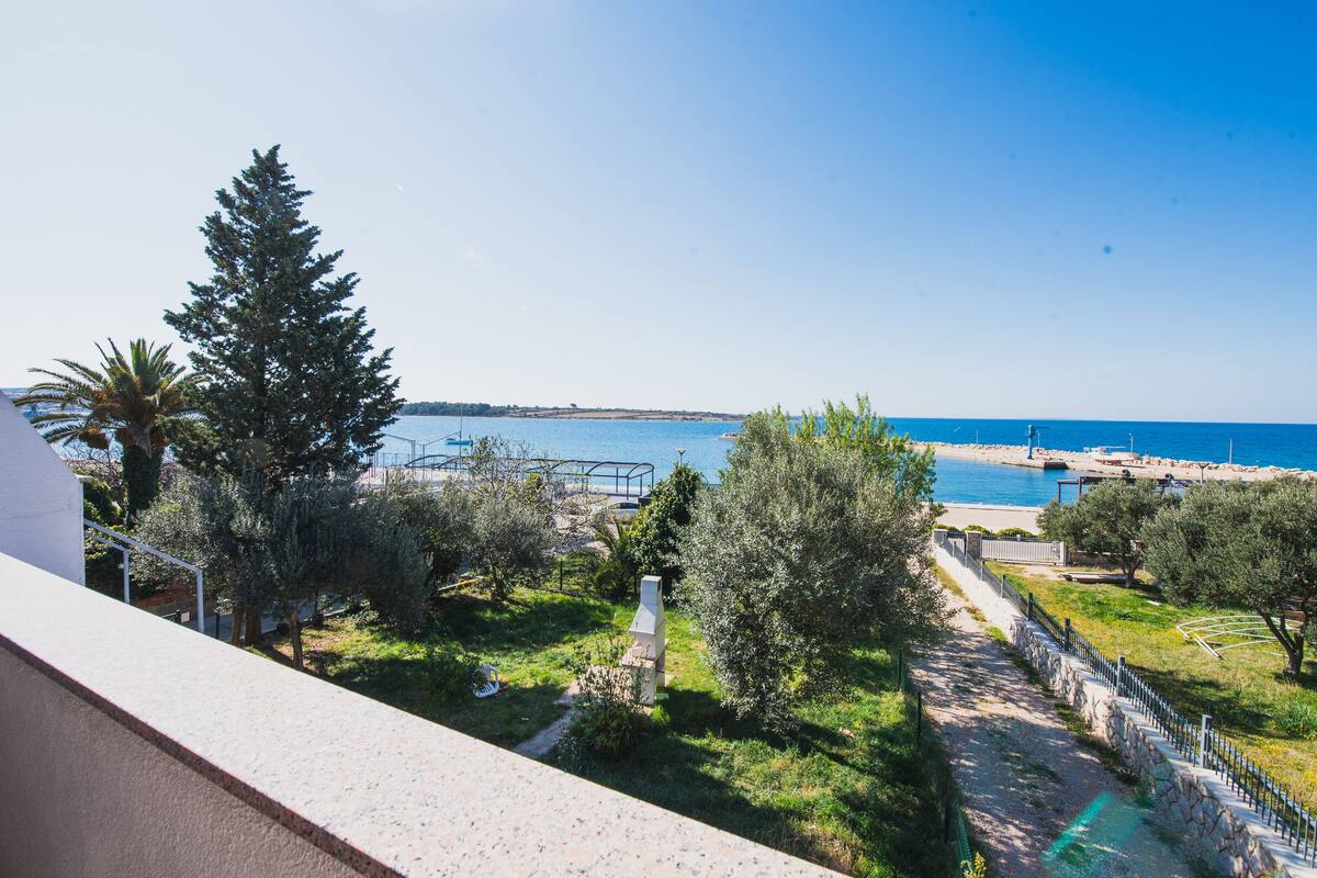 A balcony with a view of a coastal area, including a beach and a marina.