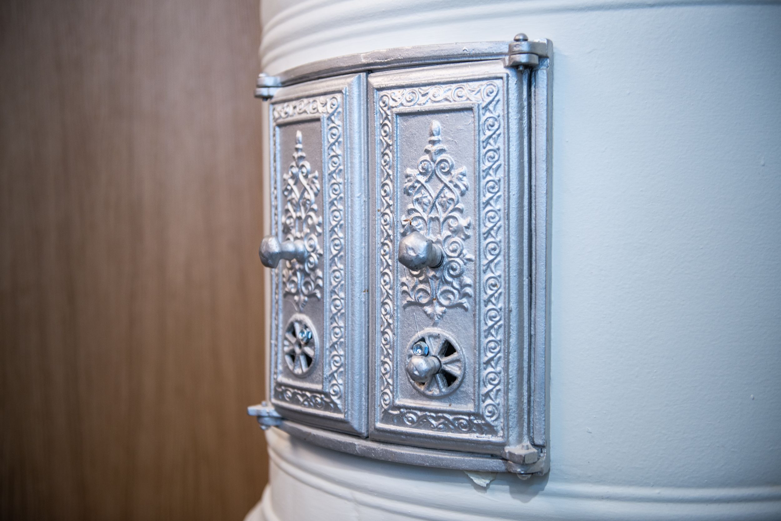 A close-up of a metallic, ornate door handle with intricate designs and a round knob.