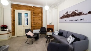 Una sala de estar con un sofá gris, sillas negras, una mesita y un panel de pared de madera.