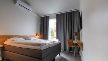 Una habitación de hotel moderna con una cama, mesita de noche, lámpara y un escritorio con silla.