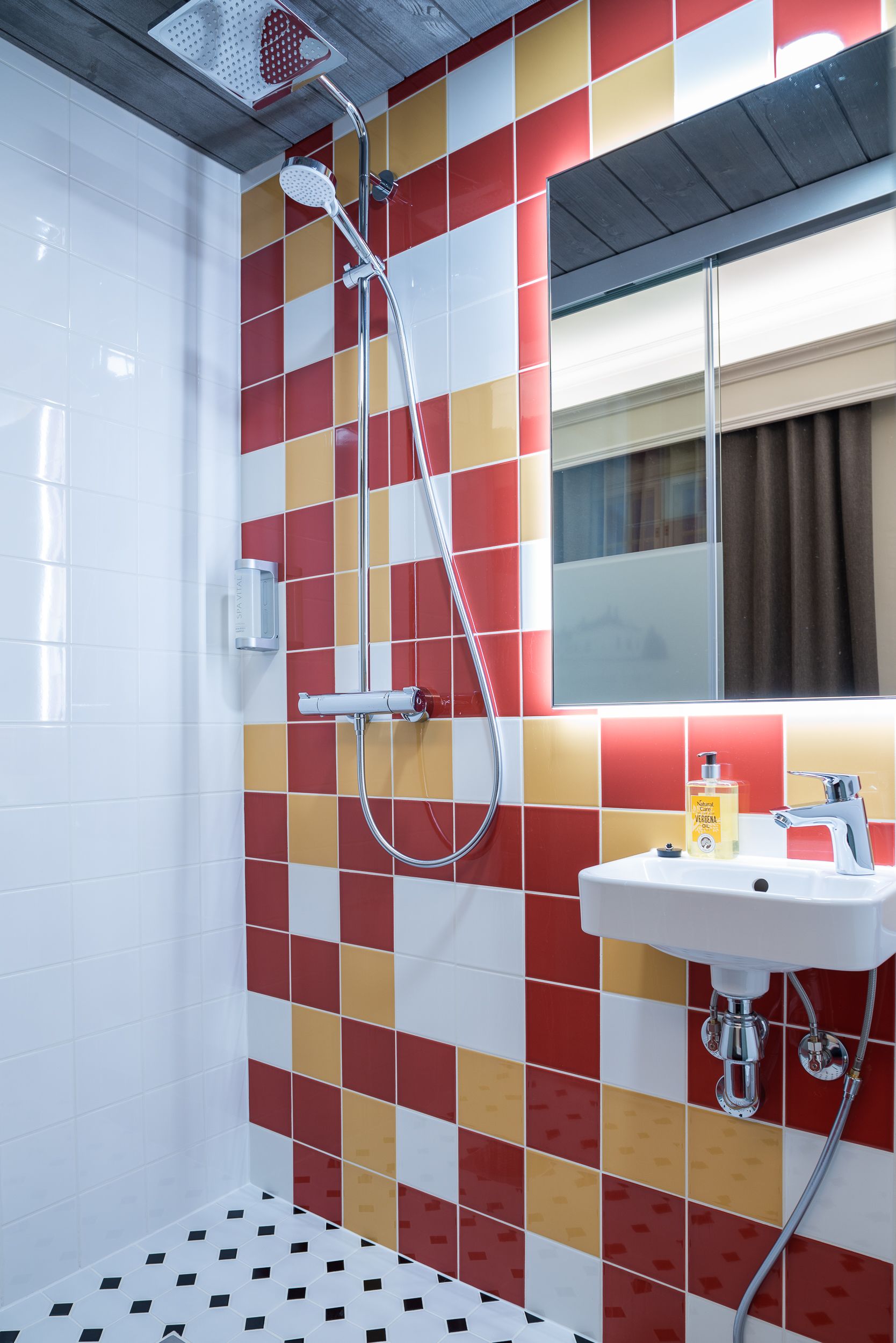 Un baño con ducha, lavamanos y espejo.
