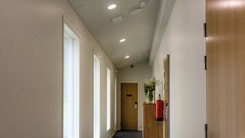 A hallway with a dark floor, white walls, and a wooden door at the end.