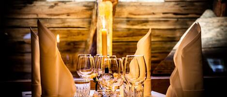A wooden interior with a table set for dining, featuring clear glassware and a lit candle.