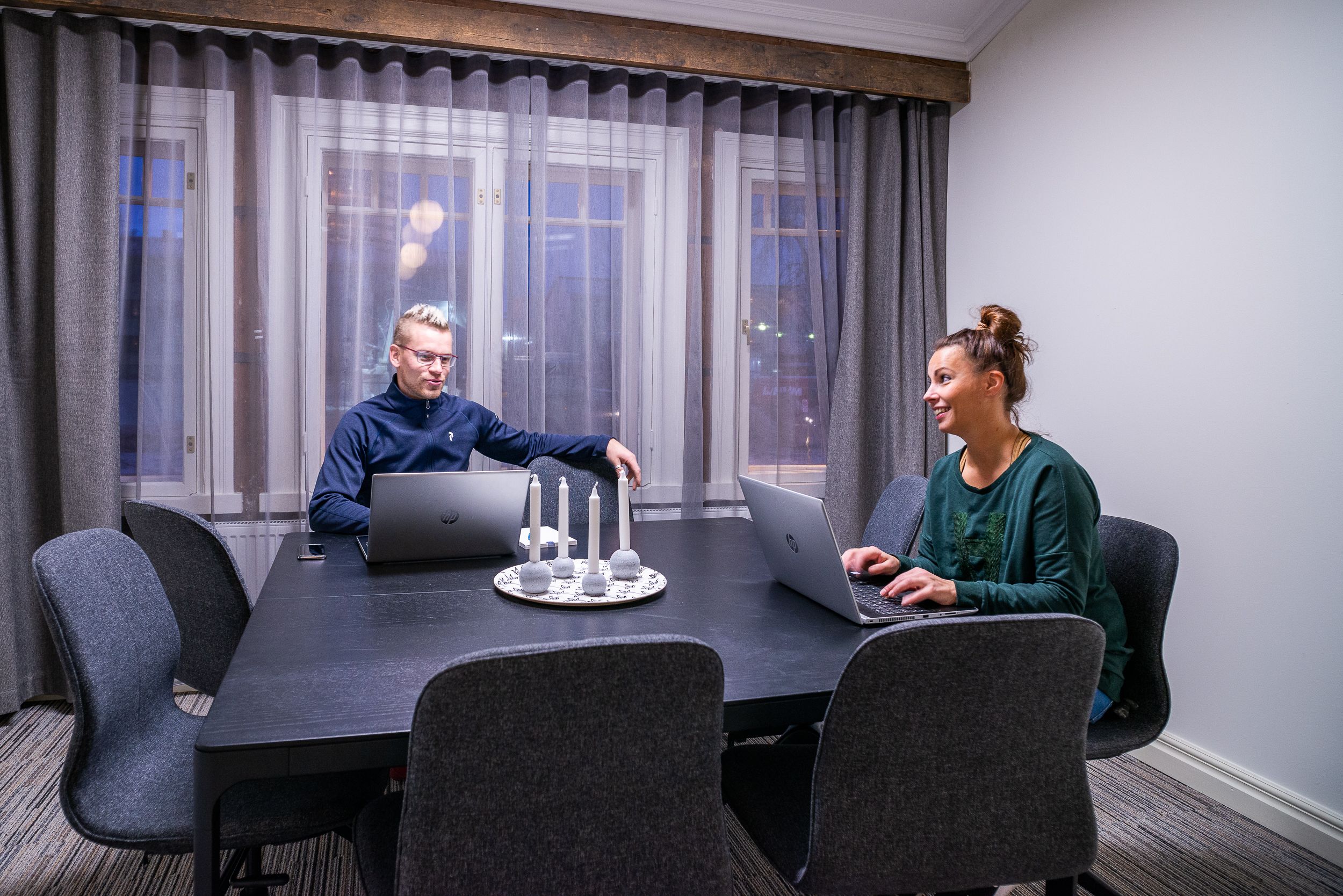 A conference room with a long table, two laptops, and a candle centerpiece.