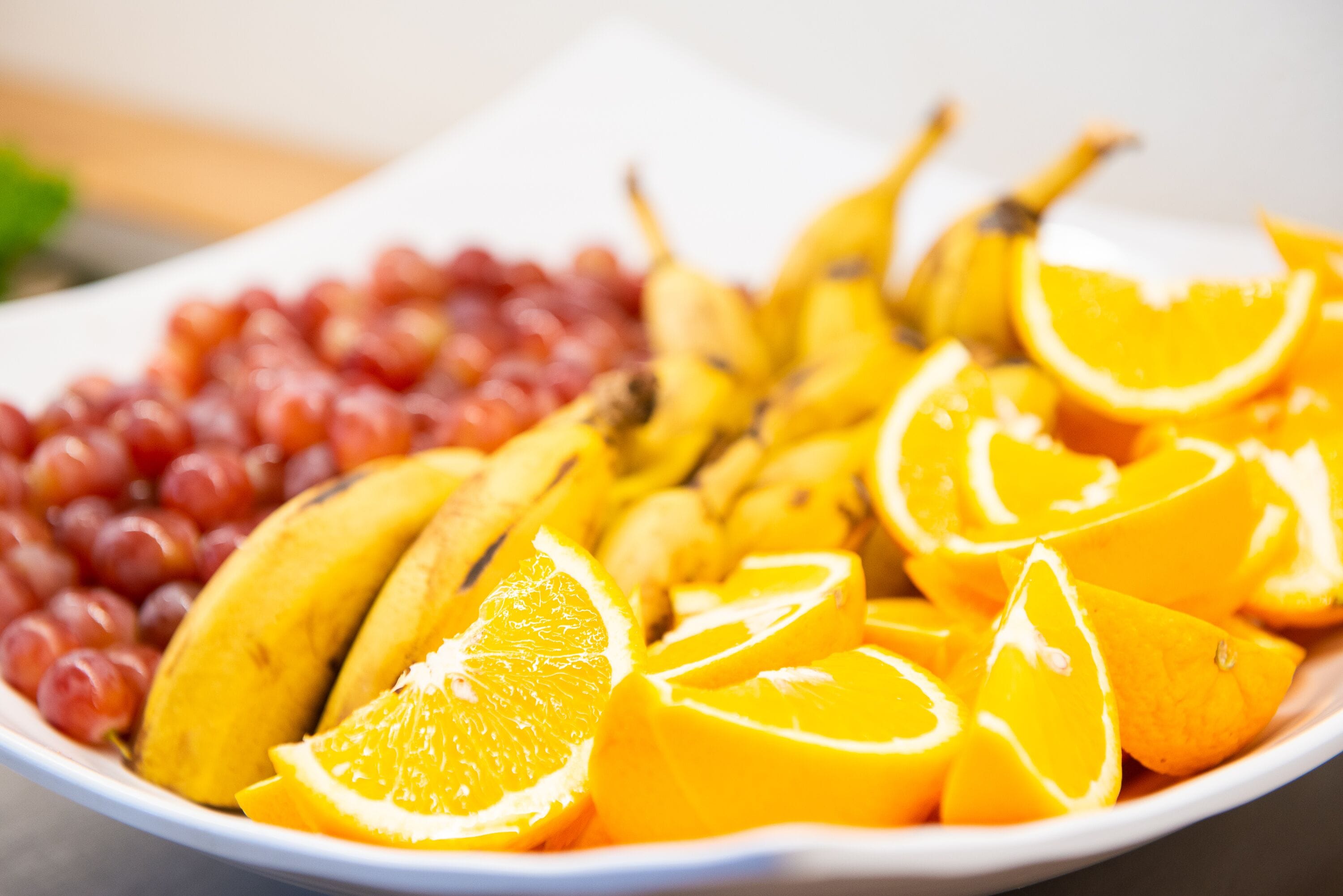 A plate of sliced oranges and bananas with grapes.