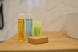 Three bottles of wellness shampoo and a bar of soap on a wooden surface. - Stil Suit (Istanbul)