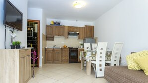 Una cocina compacta con armarios de madera, horno integrado y comedor con mesa y sillas.