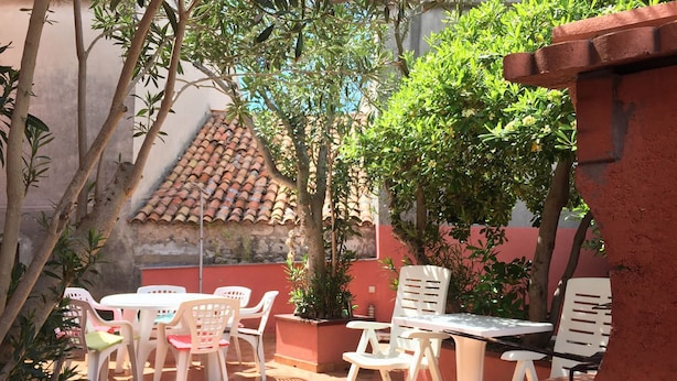 An outdoor patio with a table and chairs, surrounded by potted plants and trees. - Holiday Home Spektar (Novalja)