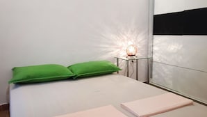 A bedroom with a bed, green pillows, a bedside table with a lamp, and a mirror on the wall. - Holiday Home Spektar (Novalja)