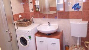 A compact bathroom with a washing machine, a sink, and a toilet. - Holiday Home Spektar (Novalja)