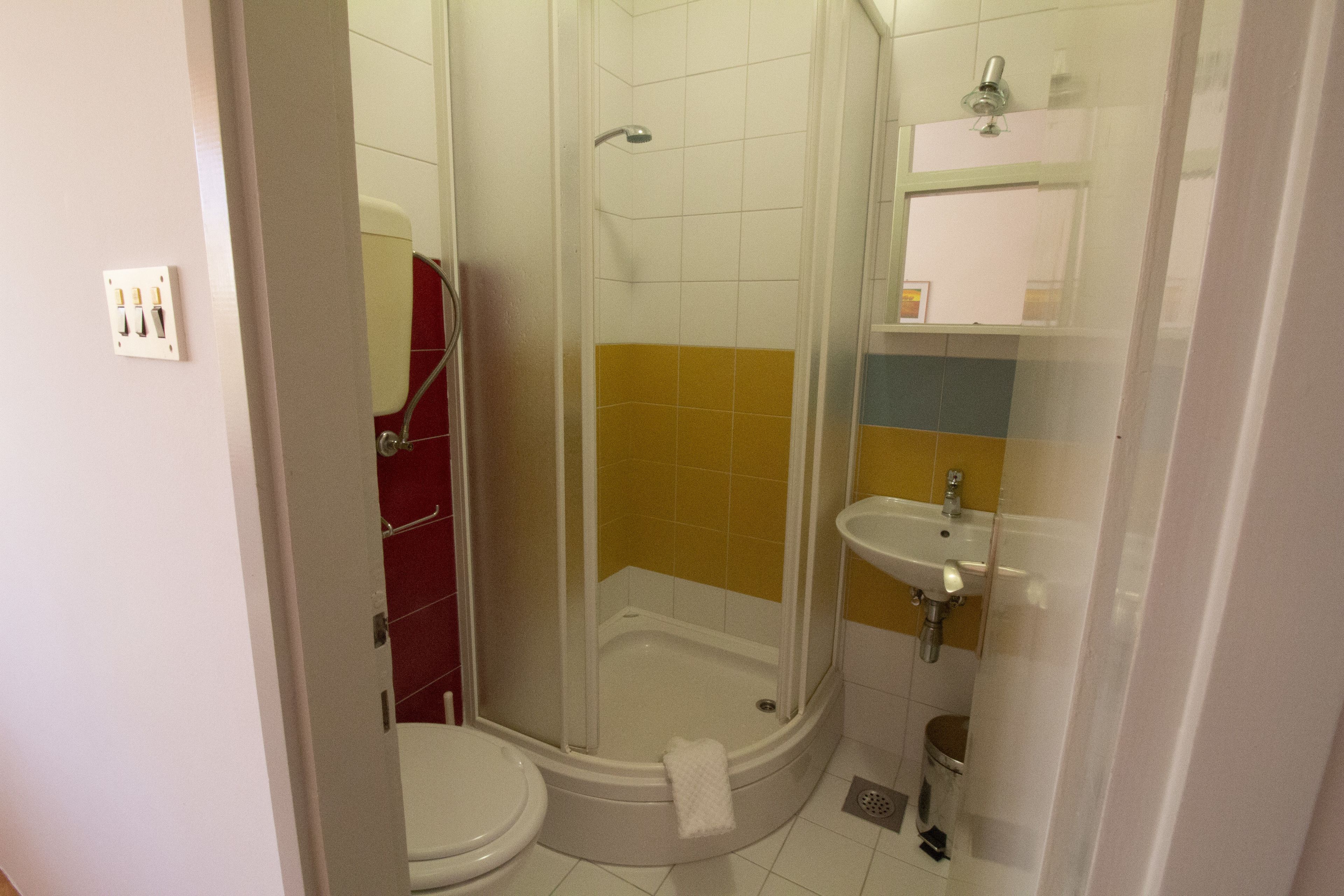 Une salle de bain équipée d’une douche, de toilettes, d’un lavabo et d’un miroir.