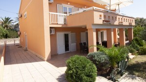 A two-story building with a balcony, outdoor seating, and a garden area. - Studios & Rooms Fiesta (Novalja)