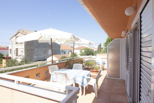 A balcony with outdoor furniture, including a table and chairs, and a large umbrella.