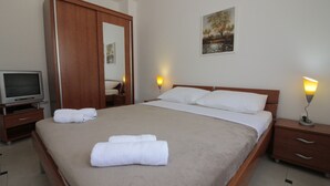 A hotel room with a large bed, two bedside tables, a TV, and a painting on the wall. - Studios & Rooms Fiesta (Novalja)