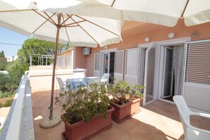 An outdoor patio area with a pool, potted plants, and a white chair. - Studios & Rooms Fiesta (Novalja)