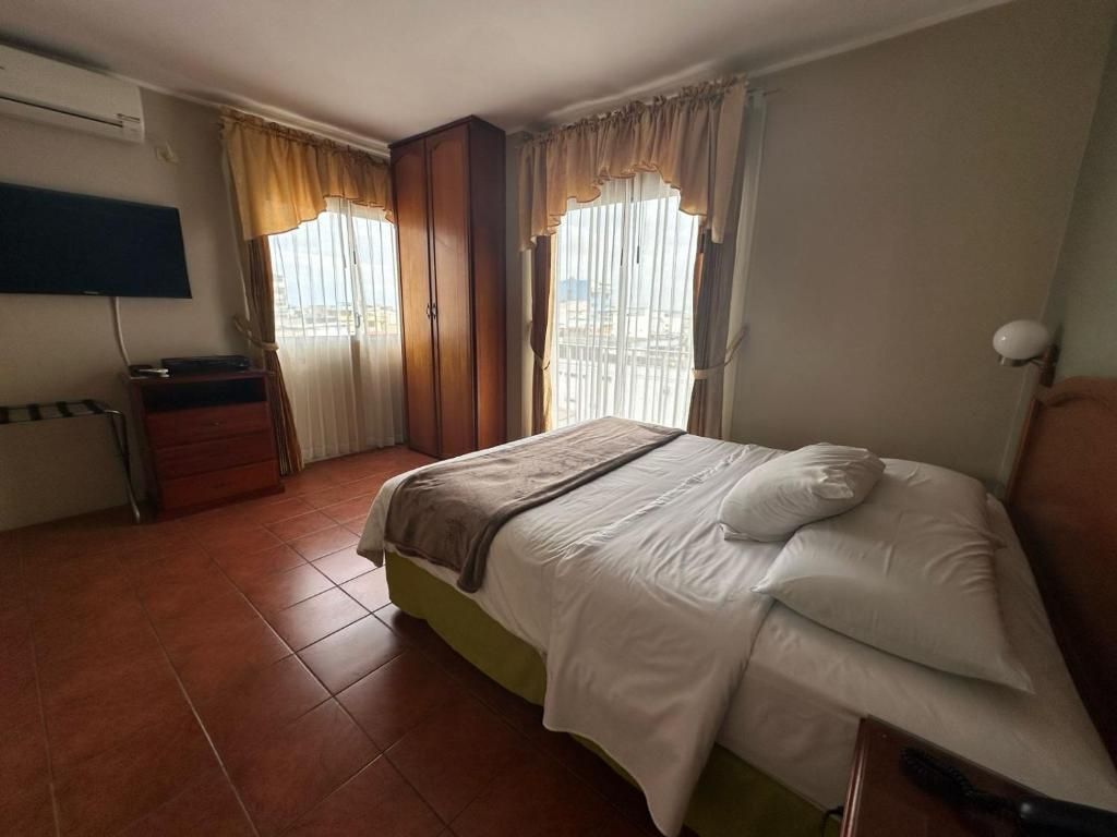 Une chambre d’hôtel avec un lit, des rideaux, une télévision et une fenêtre.