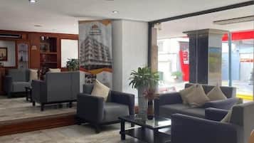 Un vestíbulo de hotel con arreglos de asientos, una mesa de recepción y un ventanal grande.