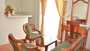 A room with a wooden dining table, four chairs, a mirror, and a window with curtains. - Grand Hotel Americano (Machala)