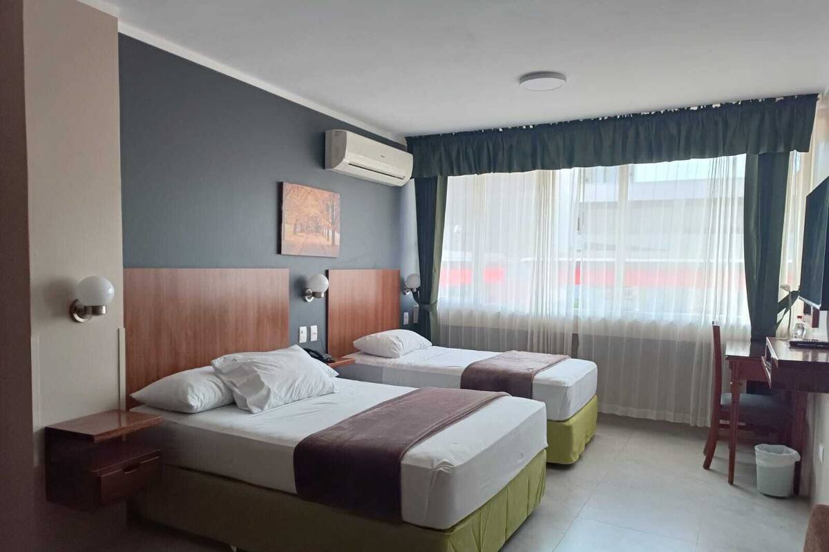 Una habitación de hotel con dos camas, un escritorio y un equipo de aire acondicionado.