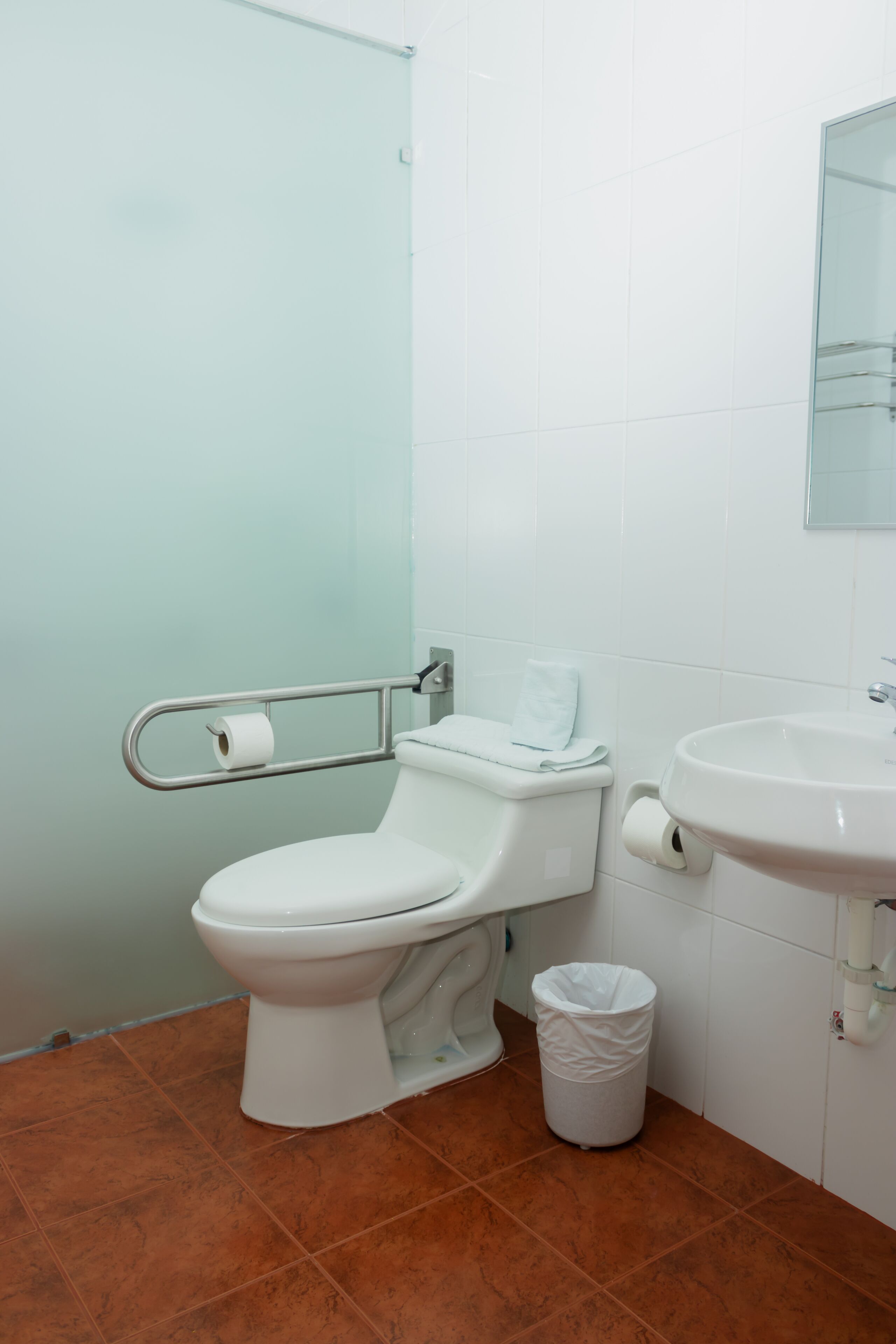 Een badkamer met een wit toilet, een witte wastafel en een afvalbak.