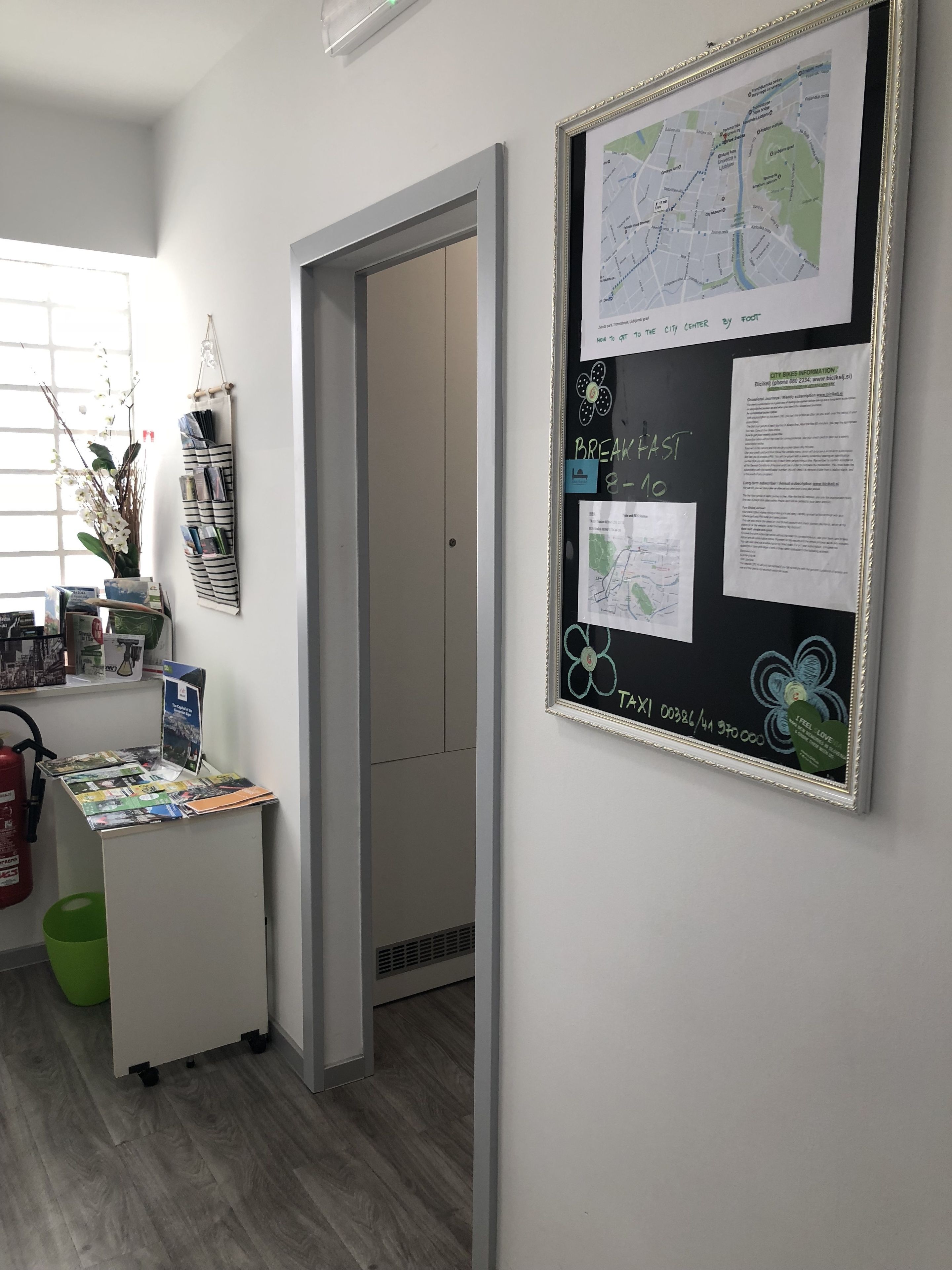 Una habitación con un escritorio mostrando folletos, un mapa en la pared y una puerta que da a otra estancia.