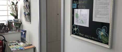 Una habitación con un escritorio mostrando folletos, un mapa en la pared y una puerta que da a otra estancia.