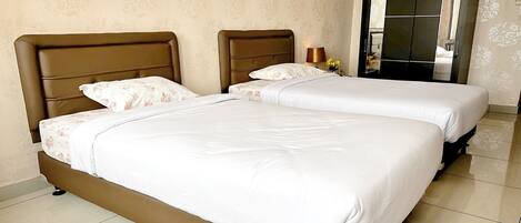 Deux lits jumeaux avec des têtes de lit marron dans une chambre d'hôtel.
