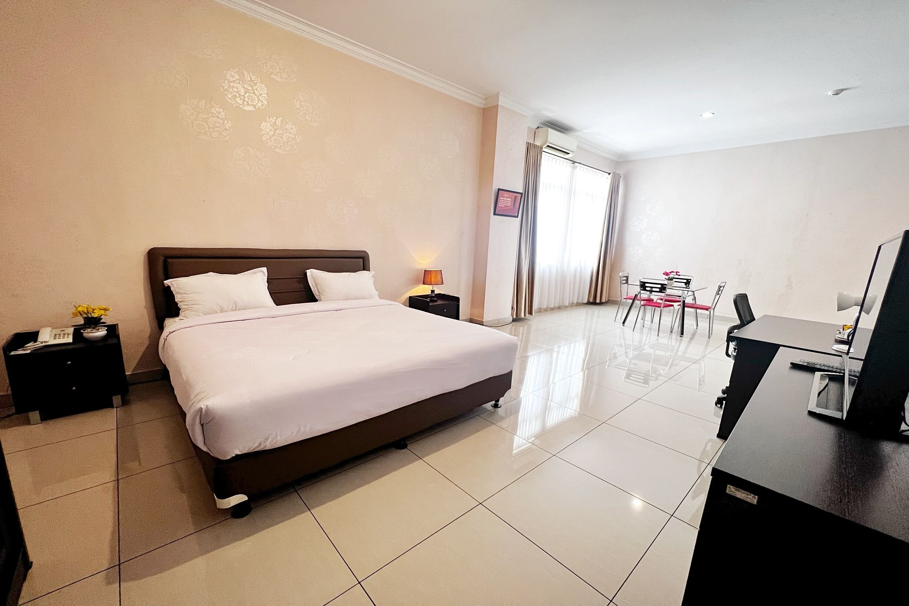A hotel room with a large bed, a desk, and a chair.