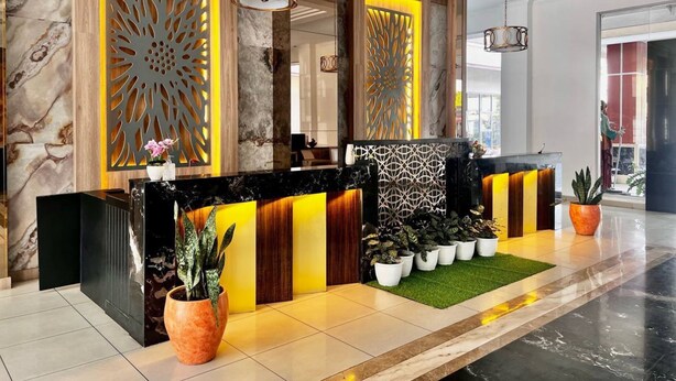 A modern reception area with a marble wall, decorative panels, and a reception desk. - Oase Guesthouse (Medan)