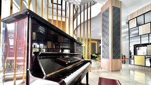 A grand piano in a spacious lobby with high ceilings, modern decor, and a large decorative column. - Oase Guesthouse (Medan)