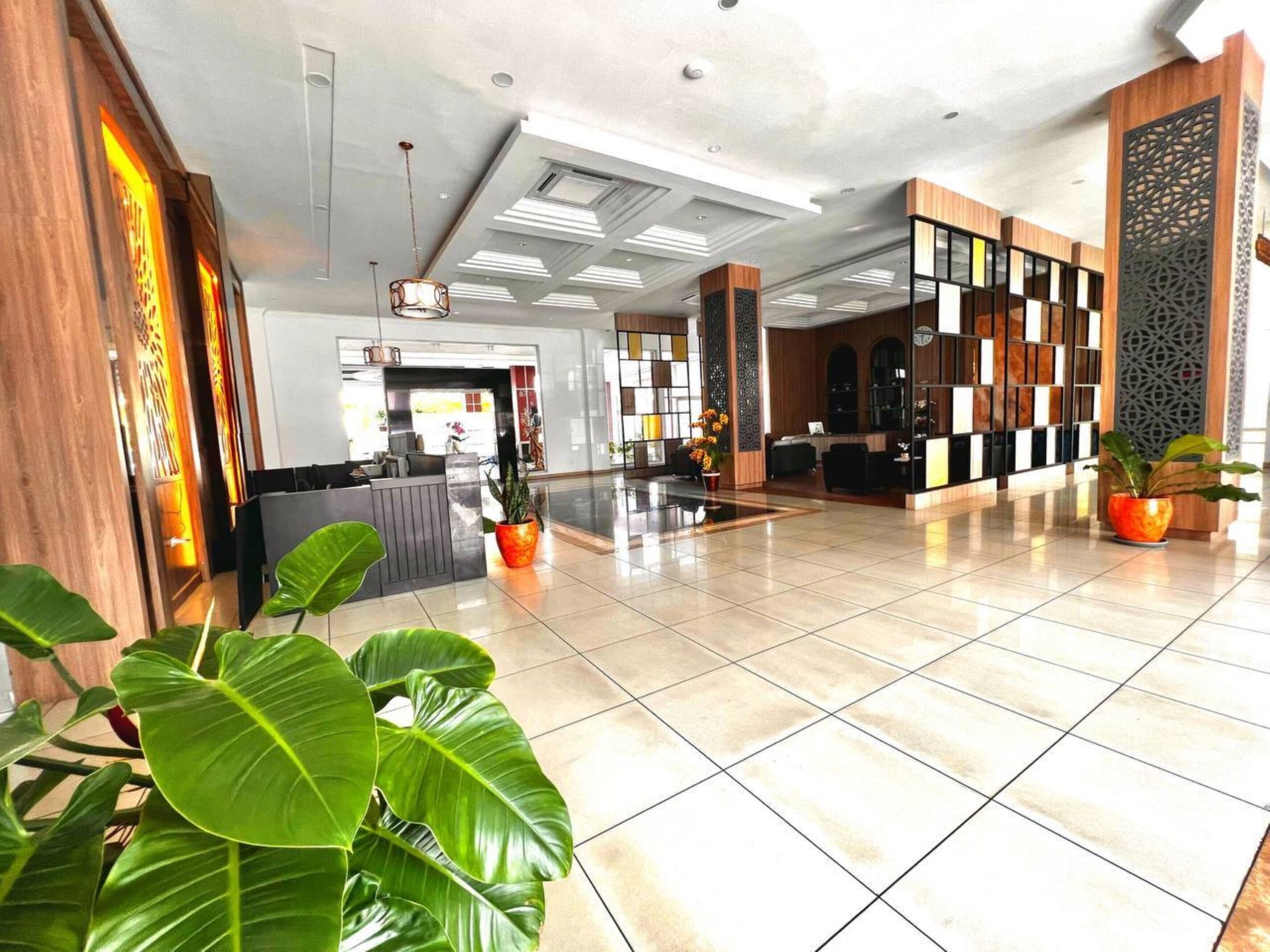 A spacious lobby with a reception desk, seating area, and decorative plants.