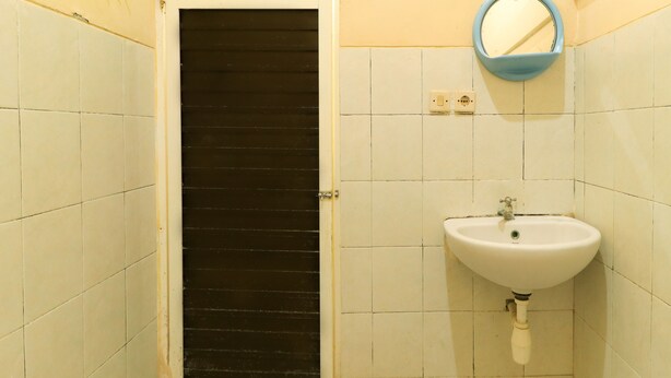Un baño con un lavabo blanco, un espejo y una puerta con manija negra.