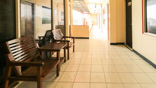 Un couloir avec des bancs en bois et un sol carrelé, qui mène à un escalier.