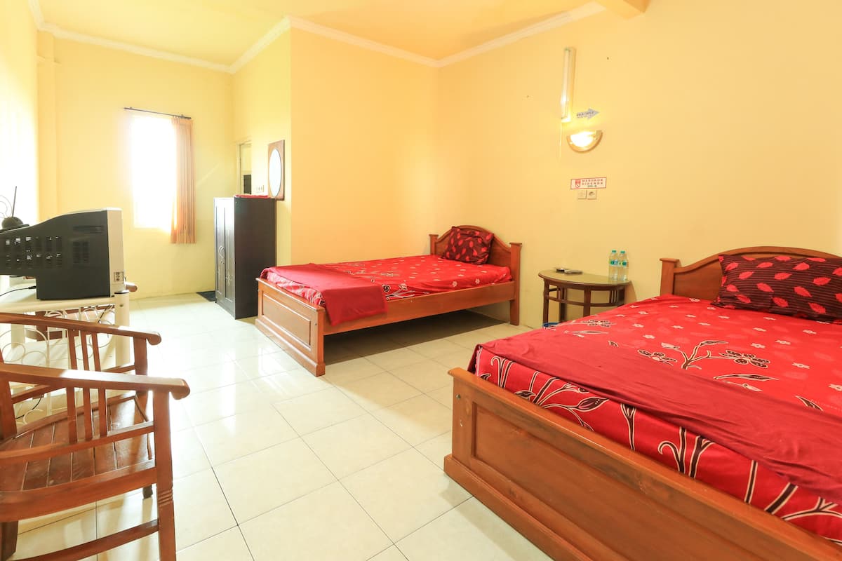 A hotel room with two wooden beds, a desk, a chair, a television, and a small table with water bottles.